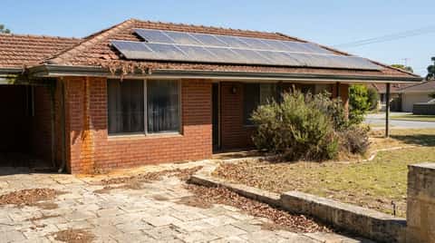 Front of a Perth brick-and-tile house showing dusty solar panels, streaked windows, leaf-filled gutters and weathered limestone paving