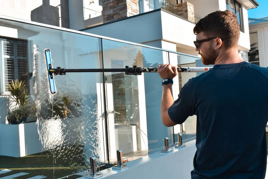 Technician squeegee-cleaning a glass balustrade on a Perth home, Purified Group window cleaning