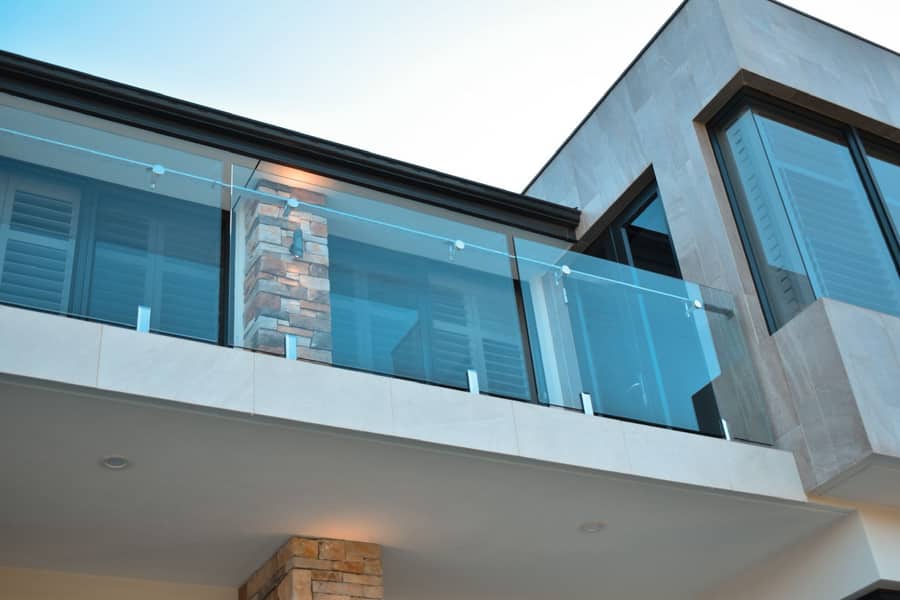 Glass balcony railing on a modern Perth home after cleaning, ocean glimpse in the background