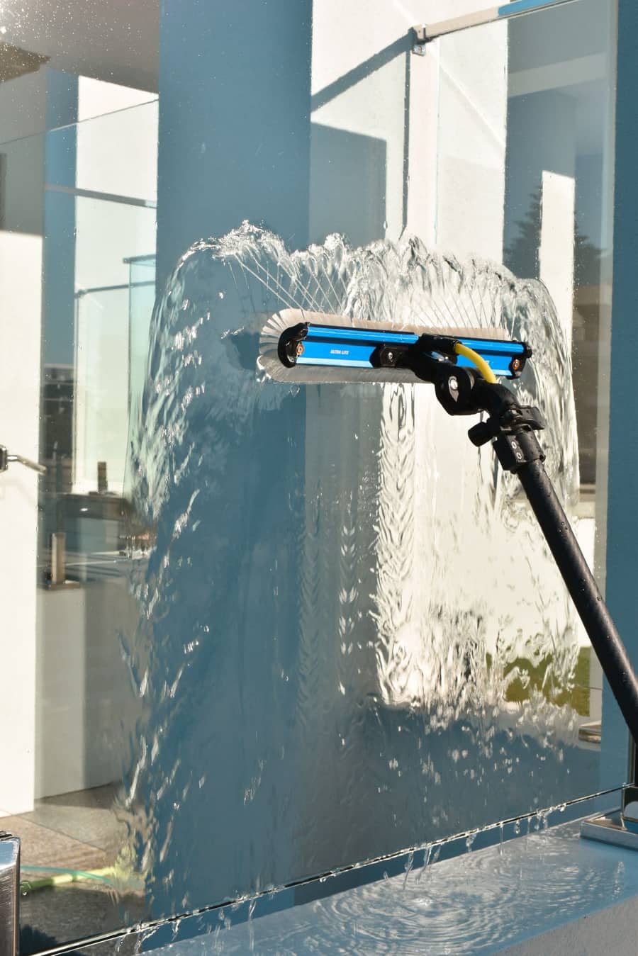 Squeegee cleaning a glass panel, suds and water mid-clean, Purified Group Perth