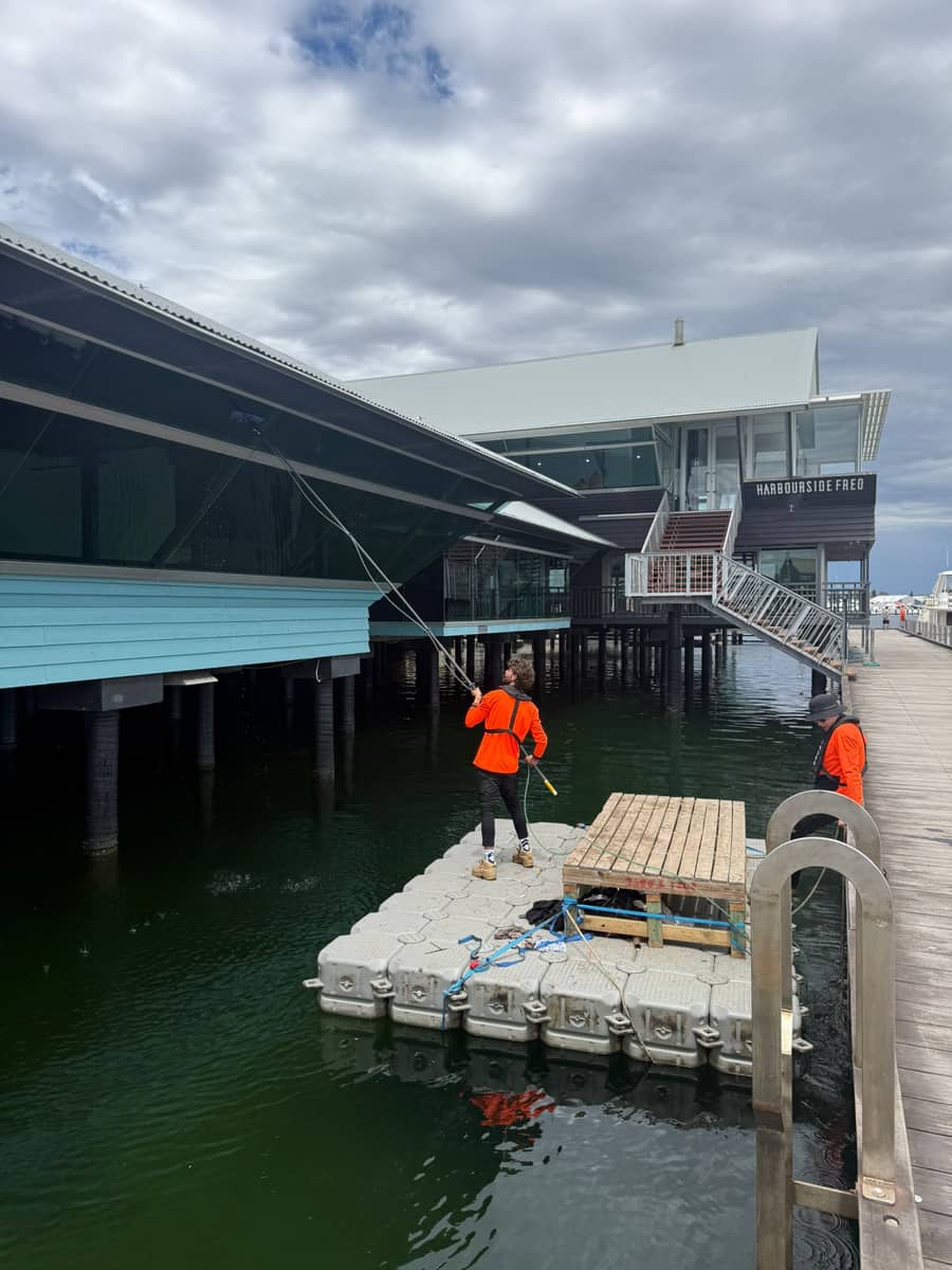Technicians cleaning windows from a floating pontoon at a waterfront venue, Purified Group Perth