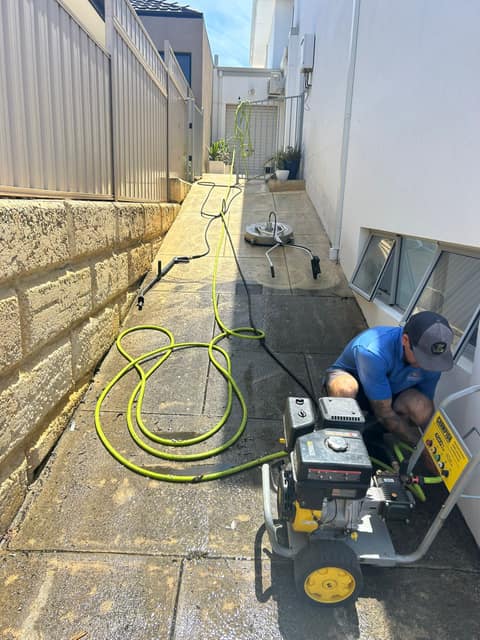 Technician setting up a petrol pressure washer and surface cleaner in a Perth laneway before a clean