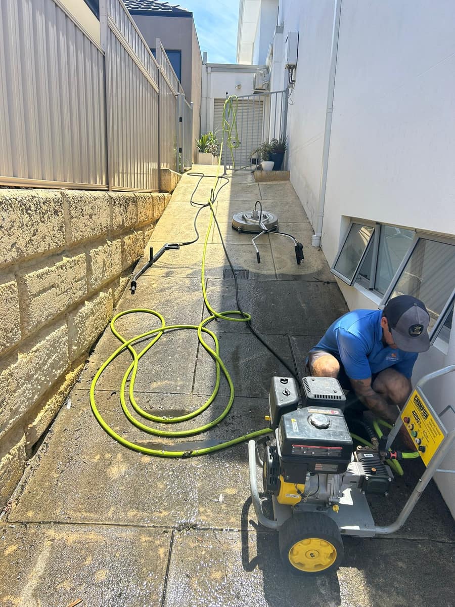 Technician setting up a petrol pressure washer and surface cleaner in a Perth laneway before a clean