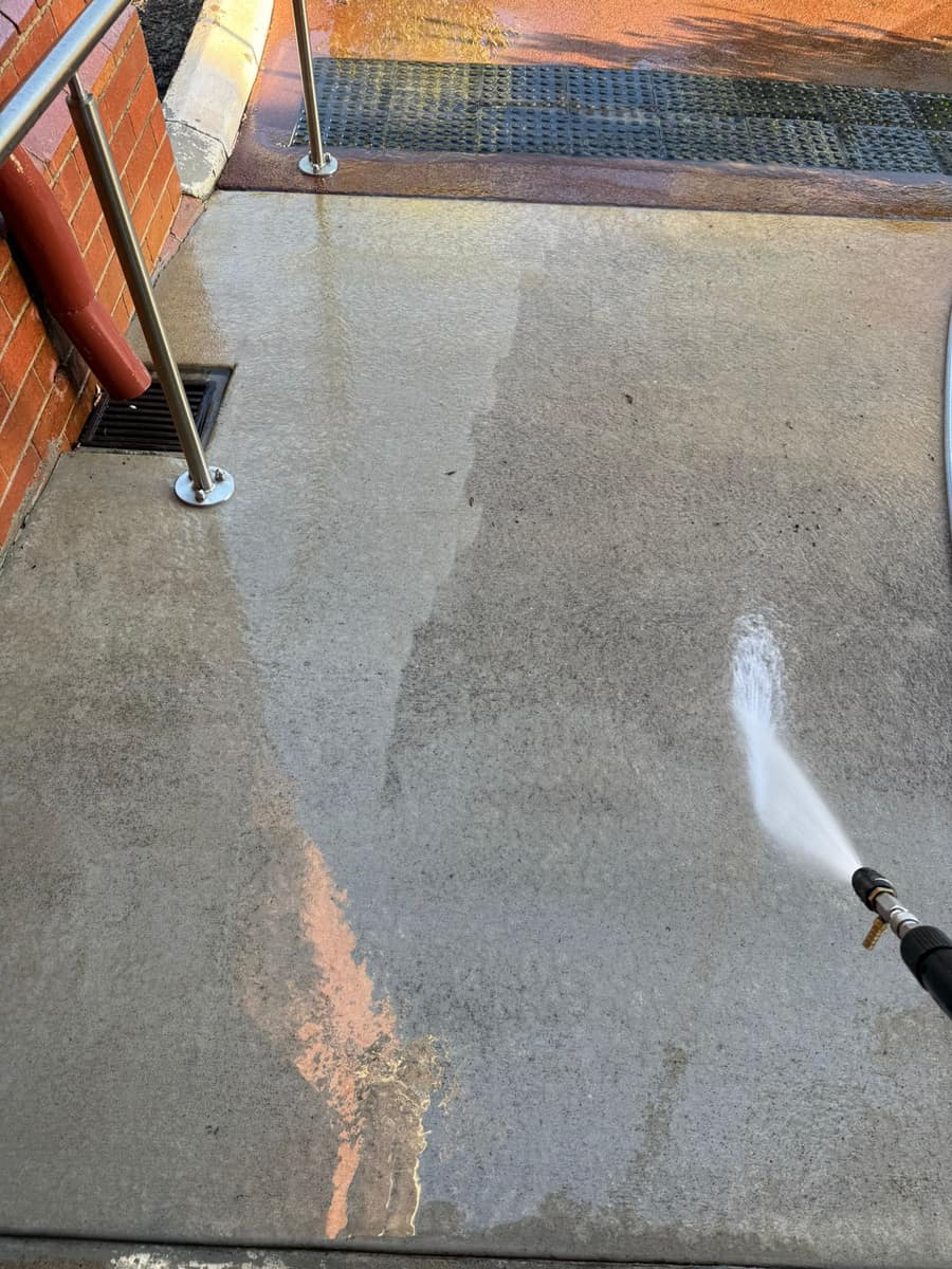 Overhead view of a paved walkway mid pressure clean, spray and runoff dividing the clean and dirty concrete, Perth