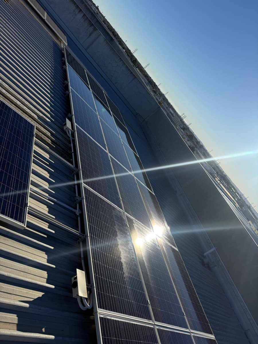 Solar panel cleaning in progress with strong sun flare and water spray, Perth