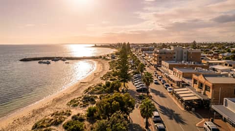 Rockingham foreshore at golden hour, esplanade shopfronts and low-rise buildings along the beach, Perth WA