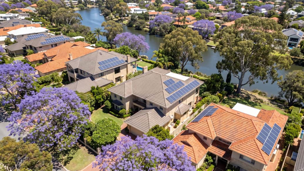 A Perth riverside suburb under jacaranda and gum trees, a home with solar panels visible, Parkwood