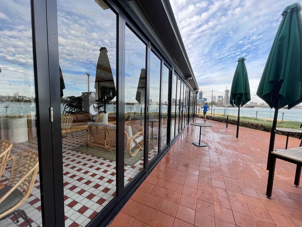 Technician cleaning floor-to-ceiling glass high above the Perth skyline and Swan River
