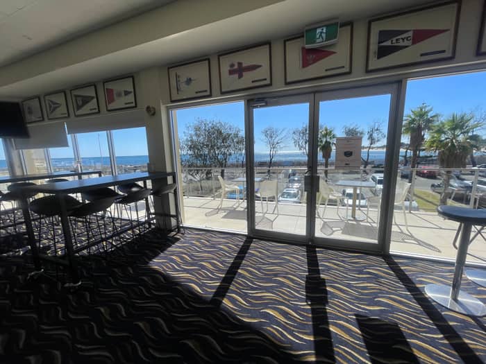 Interior lounge with glass sliding doors open to an ocean view at a Perth waterfront club
