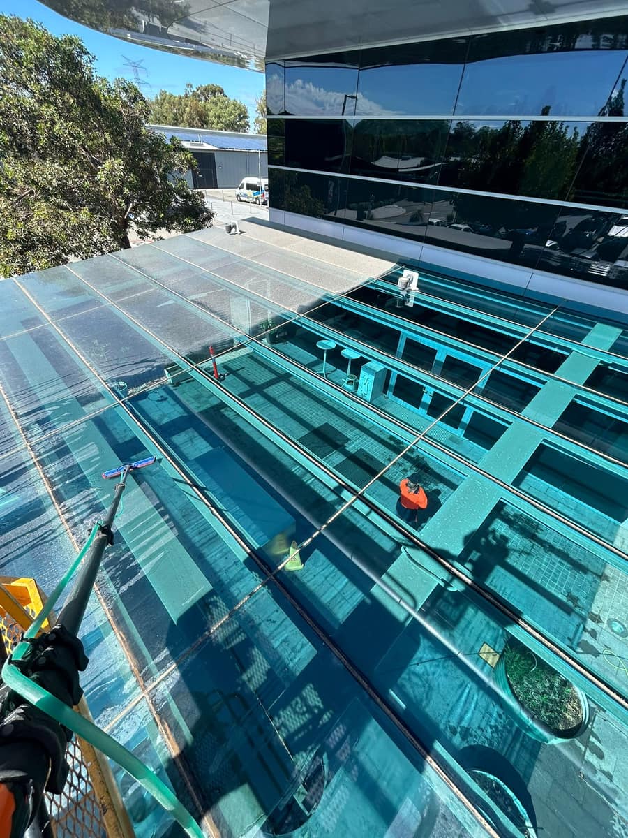 Worker cleaning a glass canopy roof structure on a commercial building, Perth